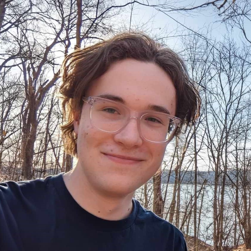 Colin LeFevre standing in a forest on a sunny day